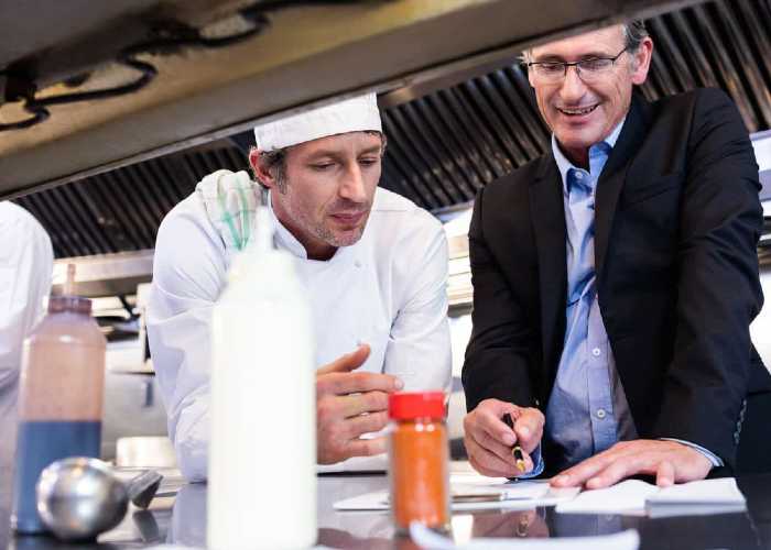 A Restaurant manager checking the allocated tasks by coordinating with his staff.